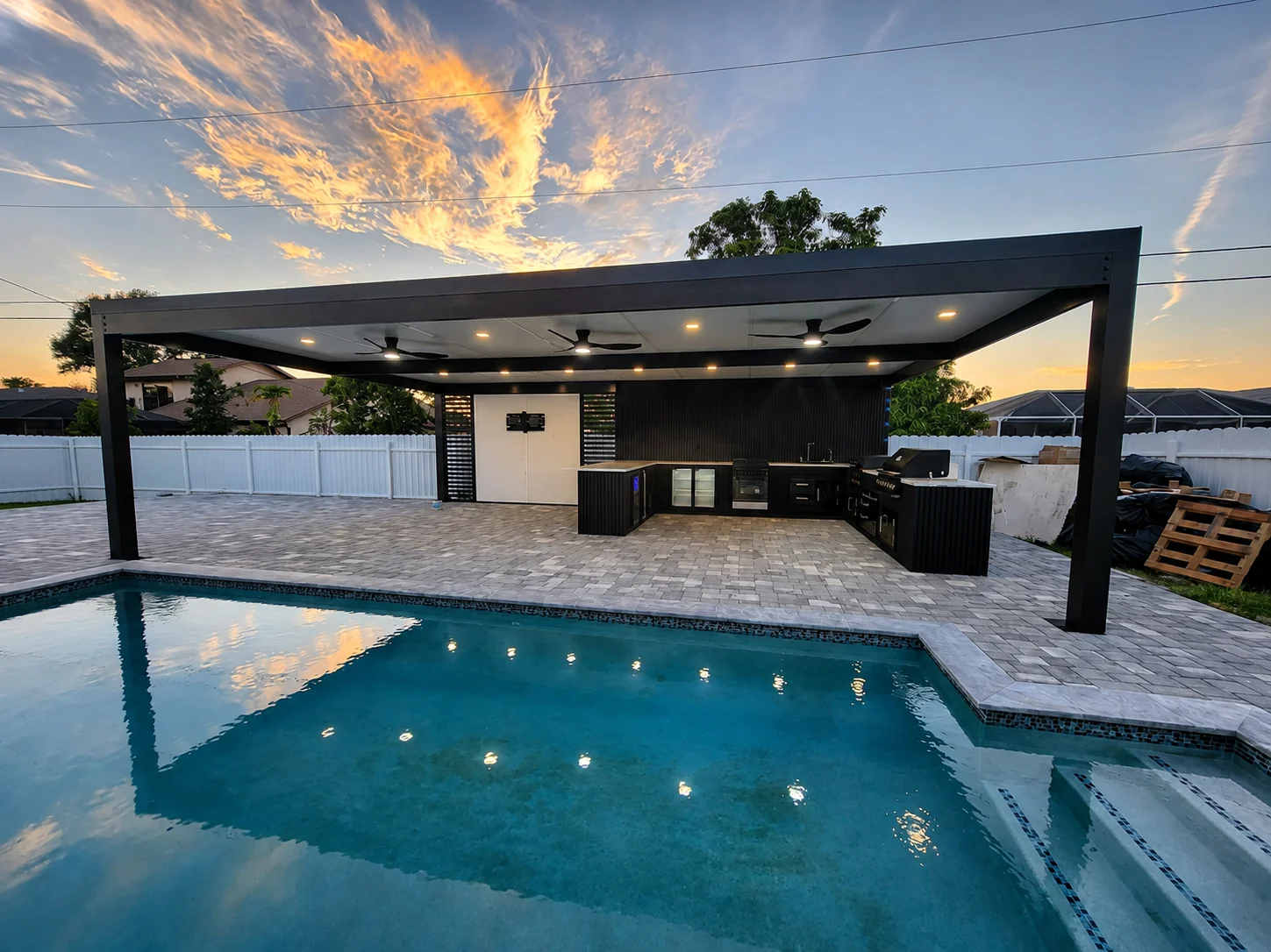 Modern poolside pergola at sunset with LED lighting and outdoor kitchen in Southeast Florida - Elite PVC